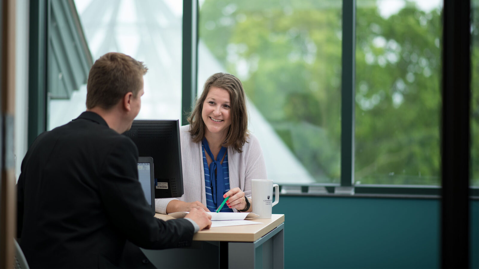 two colleagues discussing paper work at a meeting