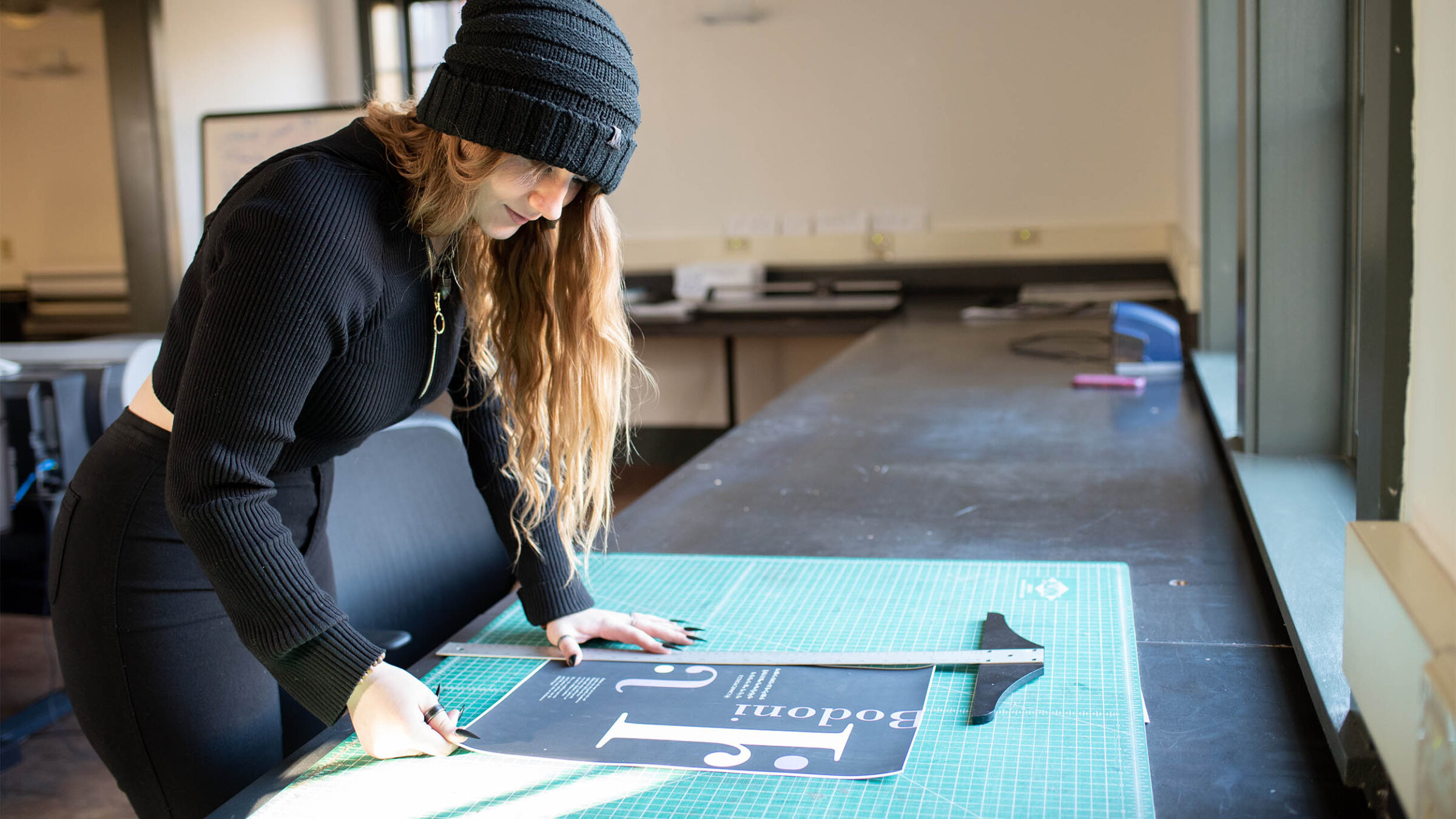 graphic design student measures a poster they made in class