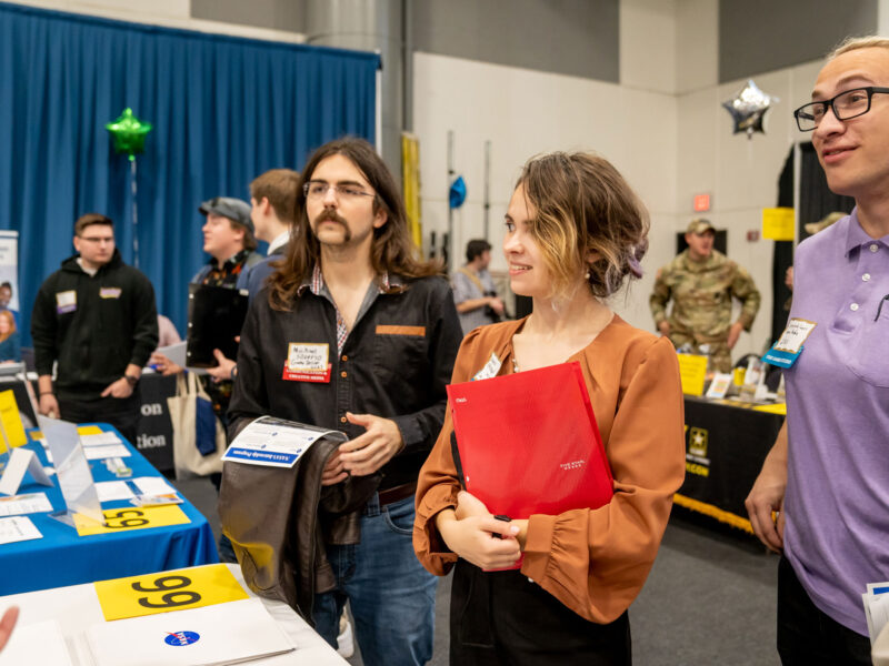 Three students stop to chat with a recruiter from NASA at the Career Fair.