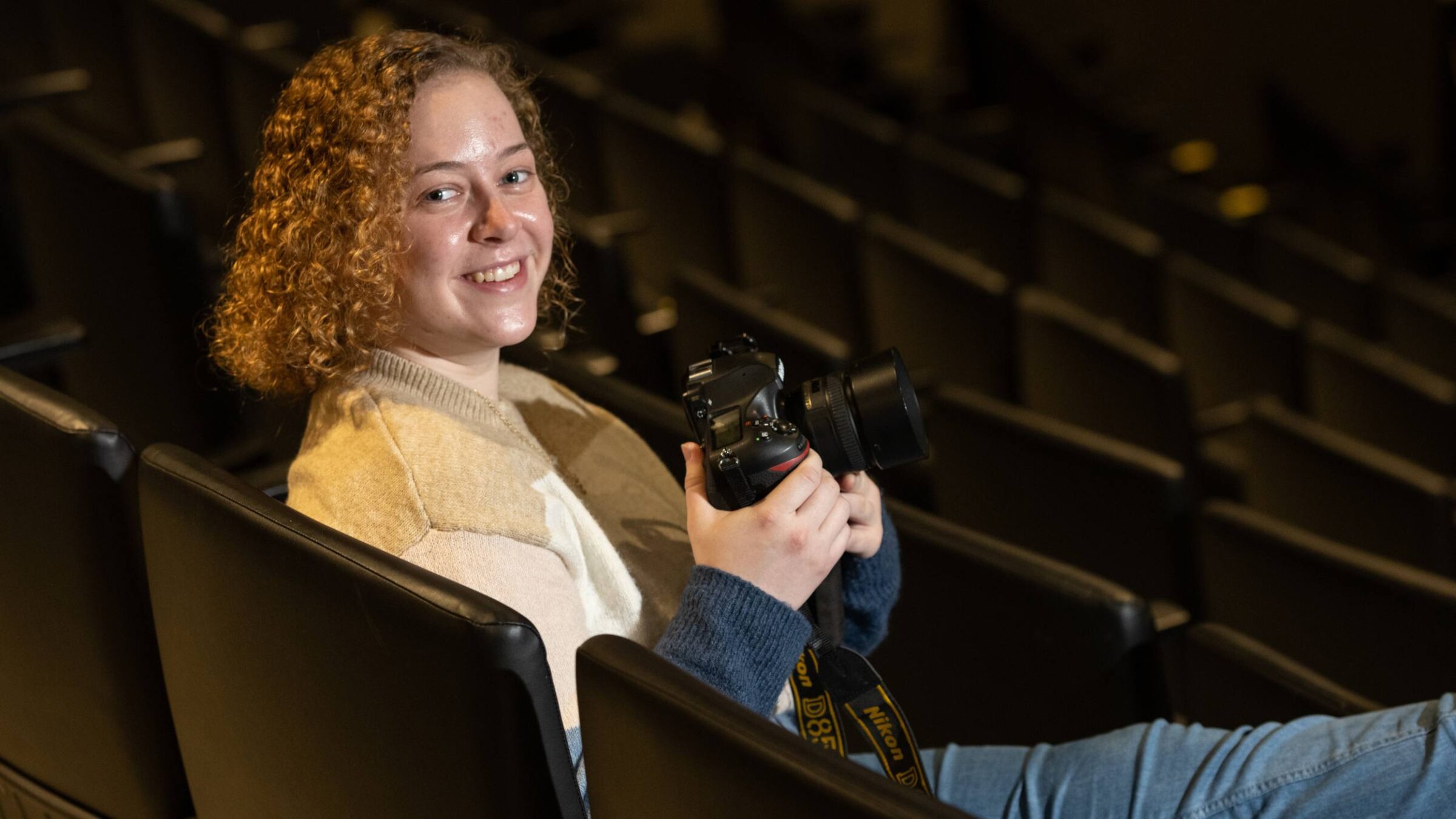 a student sitting in the auditorium smiling