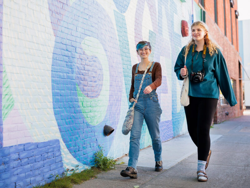 two students walking by a mural on church street