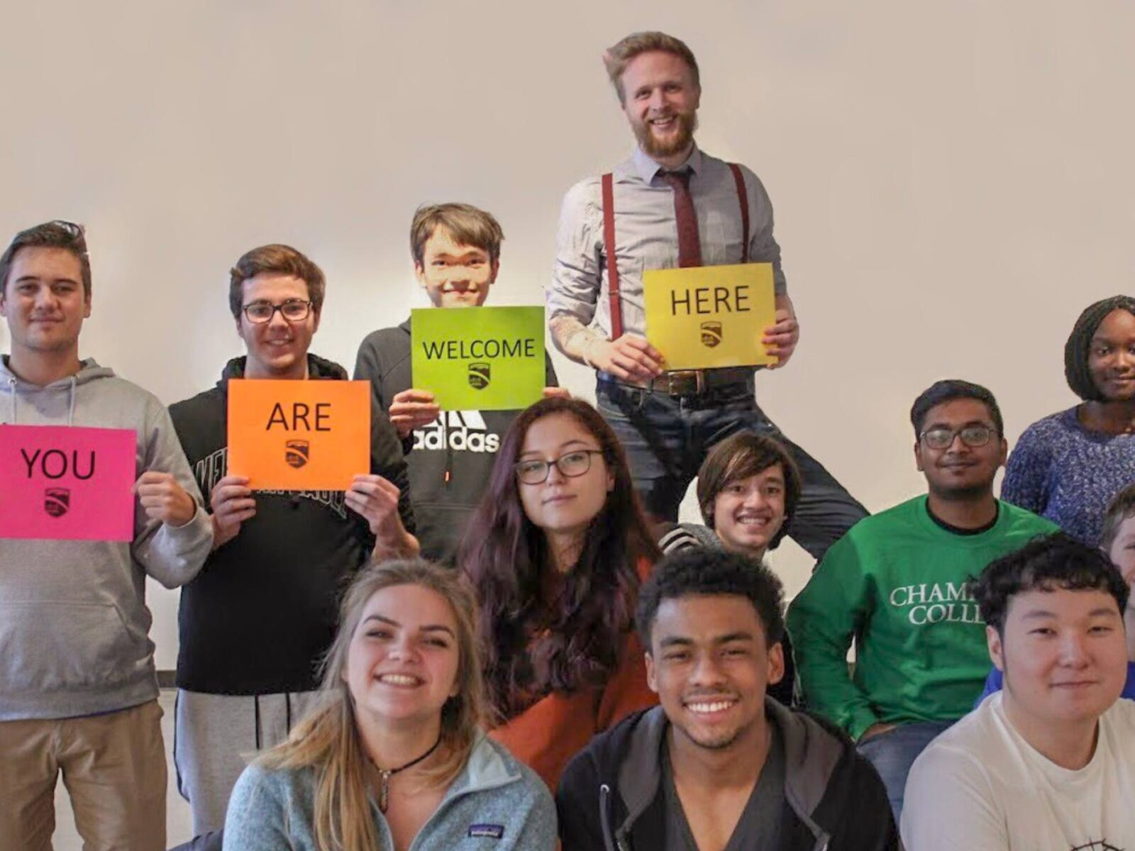Students holding signs welcoming others and smiling in a group