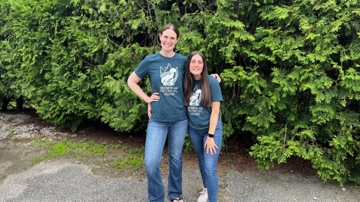 a champ 101 peer and employee facilitator pose for a photo wearing shirts that read "unearth your potential" in front of a big green hedge