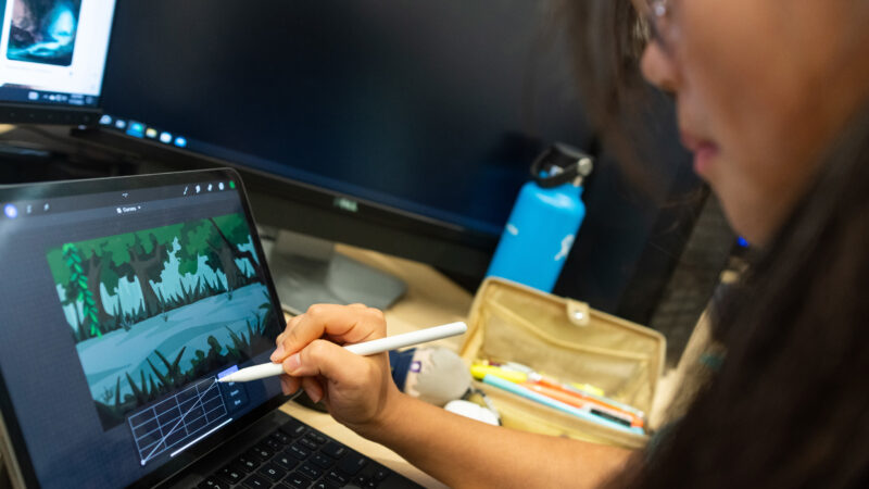 a student using an IPad and apple pencil to create digital art and animation in a classroom
