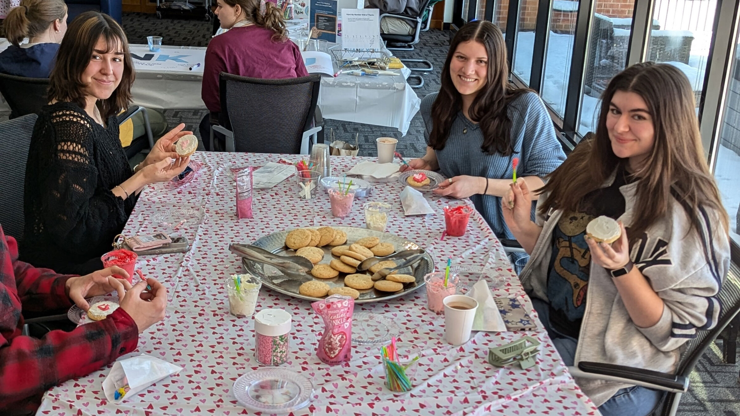 Students decorate cookies around a table.